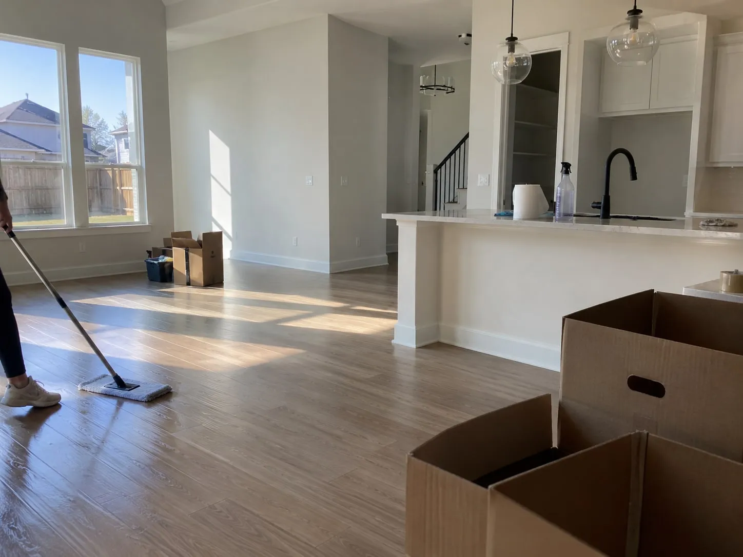 Cleaner mopping hardwood floors in an empty home during a move-out cleaning in North Texas